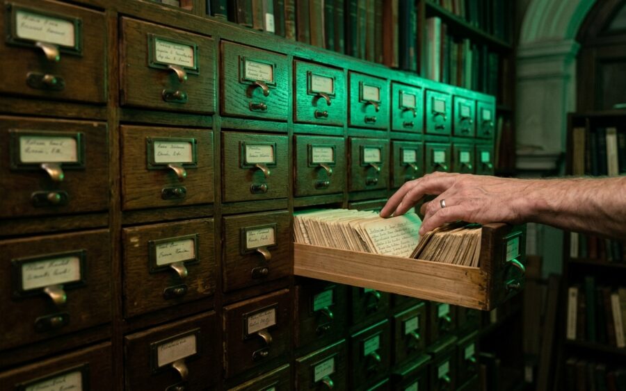 Vintage library card catalog with one drawer open showing handwritten index cards